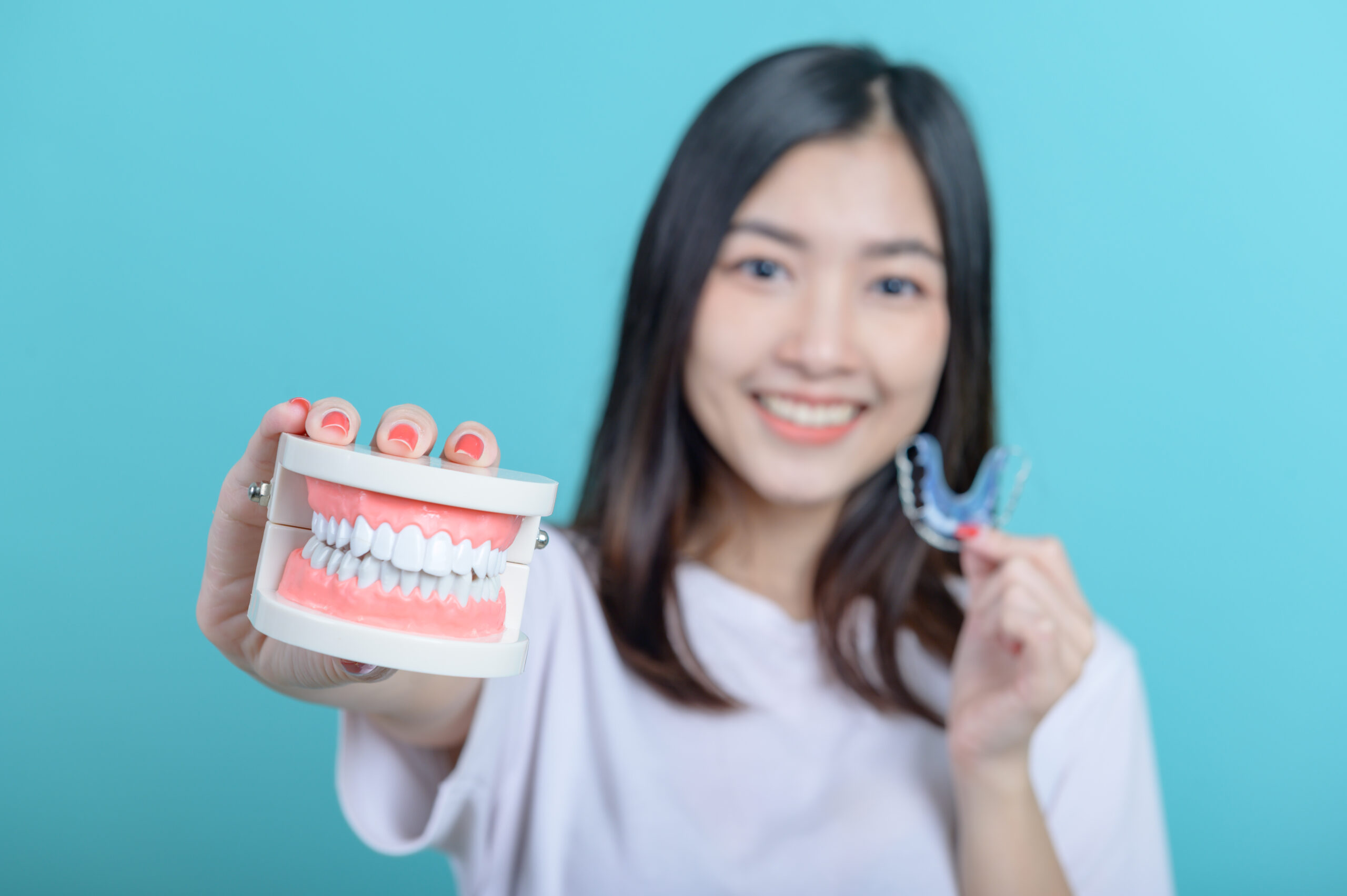 smiling-asian-woman-holding-tooth-model-blue-screen-background-dental-care-healthy-teeth Smiling Asian woman holding tooth model on blue screen background. Dental care and healthy teeth.